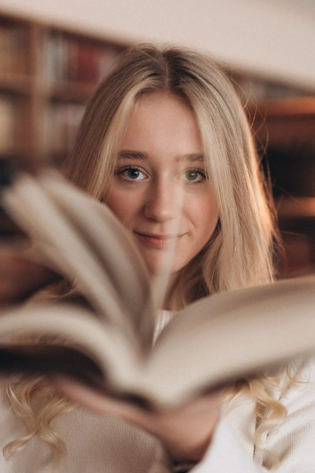 Выпускница с открытой книгой в библиотеке